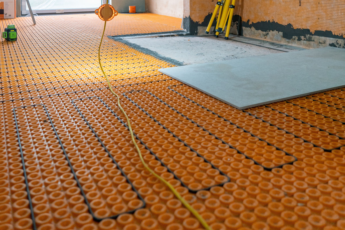 Schlüter-DITRA uncoupling membrane with underfloor heating cables before large-format porcelain tile installation.