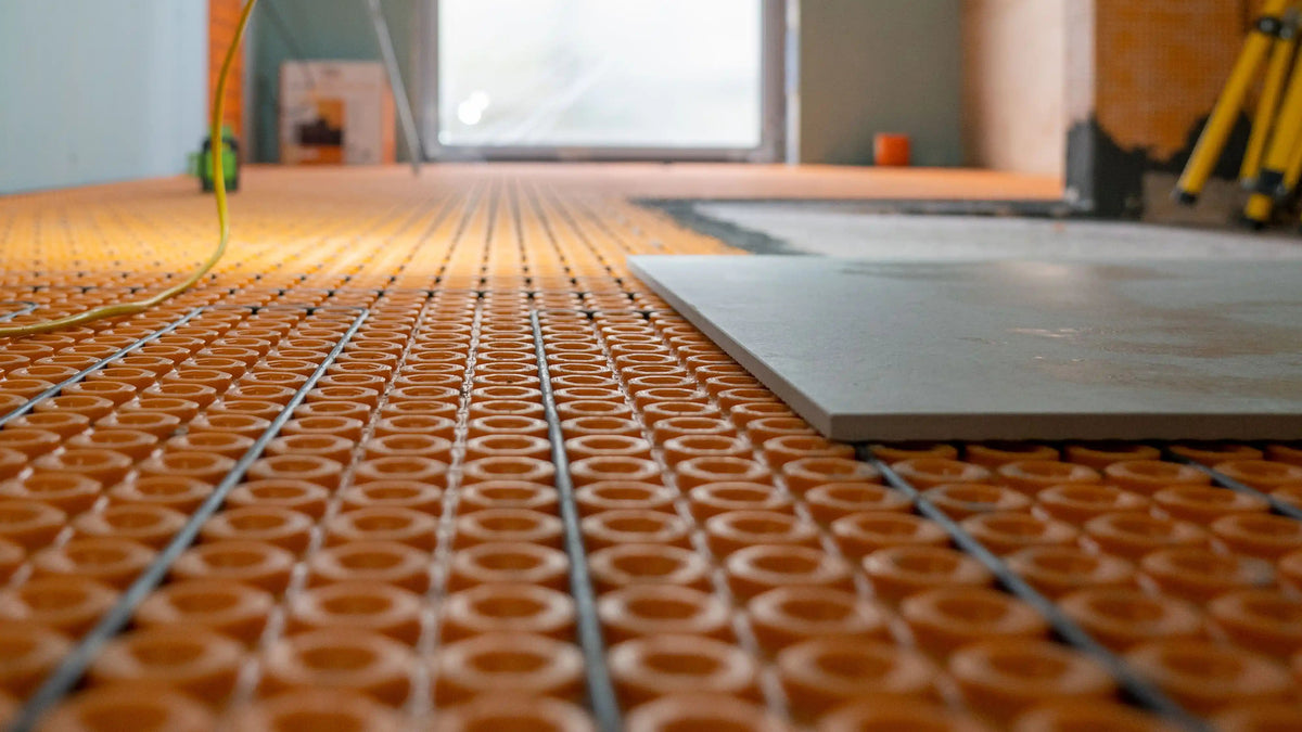 Schlüter-DITRA uncoupling membrane with underfloor heating cables before large-format porcelain tile installation.