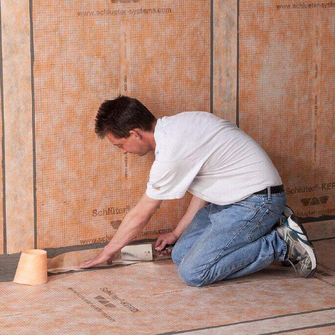 Man applying Schluter KERDI Keba Sealing Band to edges of membrane